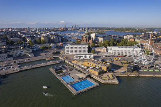 Aerial view of Helsinki Market Square and the Allas Sea Pool with swimming pools a Ferris wheel and the Uspenski Cathedral in Helsinki Uusimaa Finland.