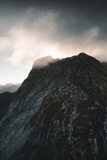View of Reinebringen mountain peak with dramatic clouds and rocky terrain in Moskenes Nordland Norway.