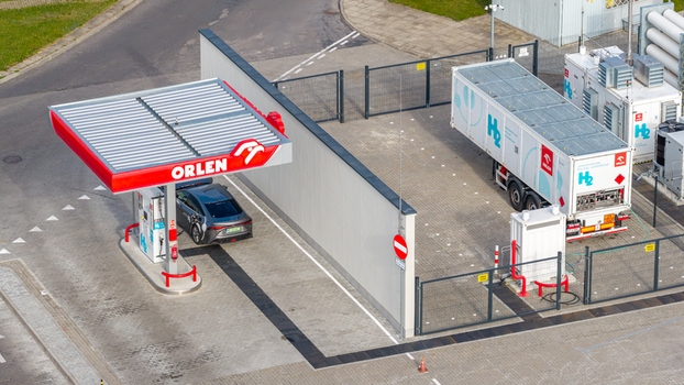 Plock Poland 10 September 2026 Aerial view of an Orlen hydrogen fuel station with a car refueling at the pump and a hydrogen storage trailer parked nearby on a paved lot. Plock Poland 10 September 2026 Aerial view of an Orlen hydrogen fuel station with a car refueling at the pump and a hydrogen storage trailer parked nearby on a paved lot.