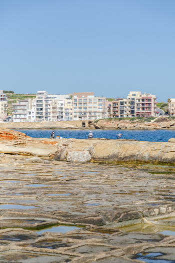 View of the rugged sun baked terrain meets the azure sea buildings stand tall against the clear sky in Marsaskala Malta creating a striking contrast Marsaskala Malta. View of the rugged sun baked terrain meets the azure sea buildings stand tall against the clear sky in Marsaskala Malta creating a striking contrast Marsaskala Malta.