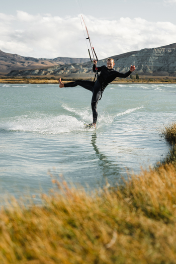 View of a man kitesurfing on a lake with mountains in the background in El Chalten Santa Cruz Province Argentina. View of a man kitesurfing on a lake with mountains in the background in El Chalten Santa Cruz Province Argentina.