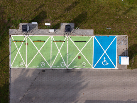 Aerial view of an electric vehicle charging station featuring green parking spaces with charging symbols and a blue accessible parking spot in Gdansk Pomeranian Voivodeship Poland. Aerial view of an electric vehicle charging station featuring green parking spaces with charging symbols and a blue accessible parking spot in Gdansk Pomeranian Voivodeship Poland.