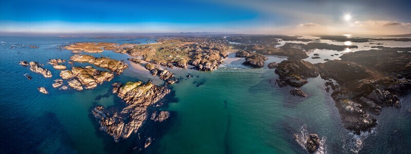 Aerial view of the rugged coastline and rocky islands of Cloughglass surrounded by turquoise waters under a clear sky at sunset in Cloughglass County Donegal Ireland. Aerial view of the rugged coastline and rocky islands of Cloughglass surrounded by turquoise waters under a clear sky at sunset in Cloughglass County Donegal Ireland.