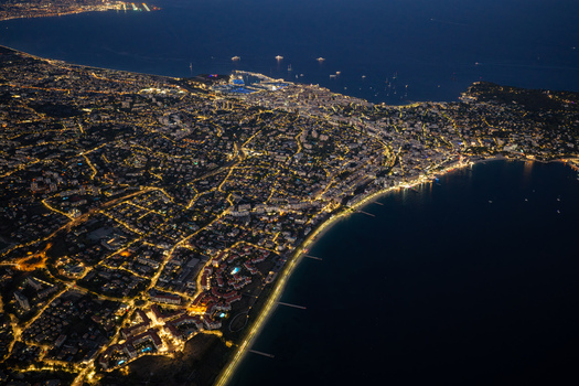 Aerial view of the illuminated city of Antibes at night featuring the glowing coastline harbor lights and dense urban grid in Antibes Provence Alpes Cote d Azur France. Aerial view of the illuminated city of Antibes at night featuring the glowing coastline harbor lights and dense urban grid in Antibes Provence Alpes Cote d Azur France.