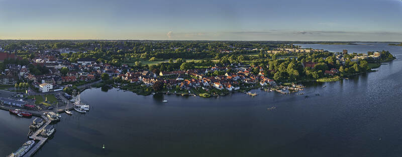Schleswig Germany 01 July 2026 Aerial view of the historic Holm fishing village along the Schlei inlet featuring traditional houses boats at the pier and the Holmer Noor landscape.