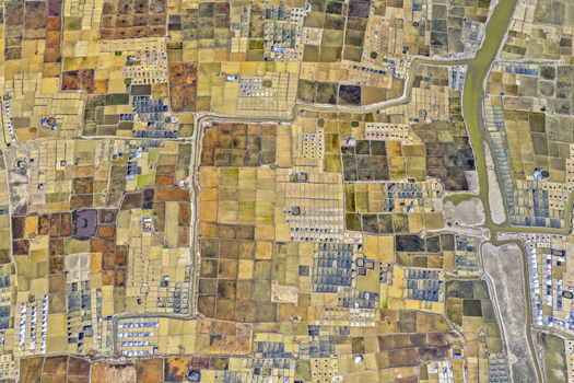 Aerial view of patchwork fields displaying a mosaic of earthy browns and muted yellows divided by narrow waterways Cox s Bazar Chittagong Division Bangladesh. Aerial view of patchwork fields displaying a mosaic of earthy browns and muted yellows divided by narrow waterways Cox s Bazar Chittagong Division Bangladesh.