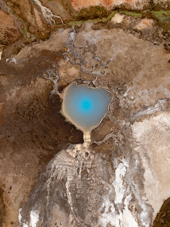 Aerial view of a vibrant blue geothermal pool surrounded by rugged volcanic earth in Reykjanesbaer Iceland. Aerial view of a vibrant blue geothermal pool surrounded by rugged volcanic earth in Reykjanesbaer Iceland.