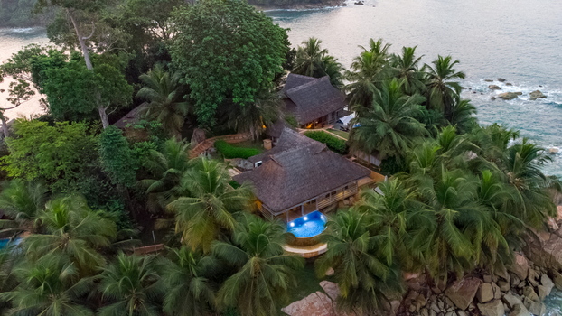 Axim Western Region Ghana 09 February 2023 Aerial view of Lou Moon Resort Eco Luxury nestled among lush palm trees and rocky coastline overlooking the ocean. Axim Western Region Ghana 09 February 2023 Aerial view of Lou Moon Resort Eco Luxury nestled among lush palm trees and rocky coastline overlooking the ocean.