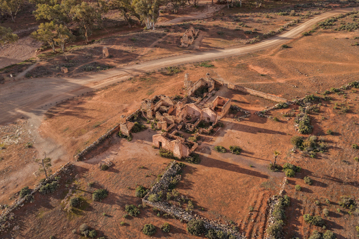 Aerial view of the historic stone ruins of Kanyaka Station surrounded by arid red earth and sparse vegetation in Flinders Ranges South Australia Australia.