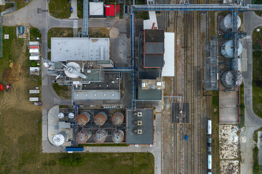 Aerial view of an industrial grain processing facility featuring large silos complex piping systems and adjacent railway tracks in Breclav South Moravian Region Czechia.