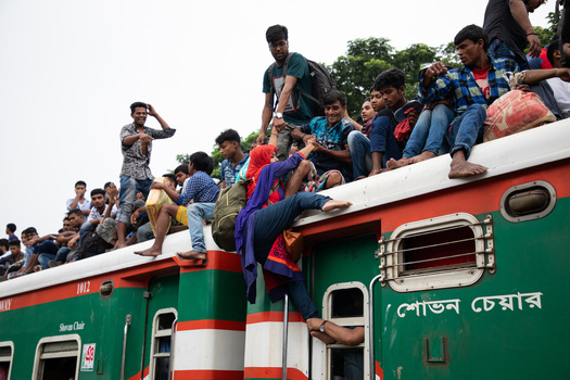 Dhaka Bangladesh 15 June 2018 View of people climbing onto the roof of a crowded train at Airport Railway Station with a woman being helped up by others during a commute. Dhaka Bangladesh 15 June 2018 View of people climbing onto the roof of a crowded train at Airport Railway Station with a woman being helped up by others during a commute.