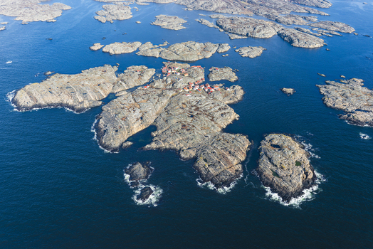 Aerial view of Flatholmen in the Bohuslan archipelago featuring rocky terrain and small houses surrounded by the blue sea in Skarhamn Vastra Gotalands lan Sweden. Aerial view of Flatholmen in the Bohuslan archipelago featuring rocky terrain and small houses surrounded by the blue sea in Skarhamn Vastra Gotalands lan Sweden.