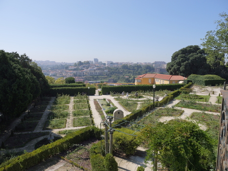 View of the manicured gardens of the Crystal Palace with lush hedges stone paths and a yellow building overlooking the cityscape of Porto Porto District Portugal. View of the manicured gardens of the Crystal Palace with lush hedges stone paths and a yellow building overlooking the cityscape of Porto Porto District Portugal.