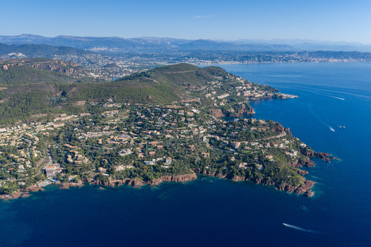 Aerial view of Le Trayas with red rock cliffs lush Mediterranean vegetation and coastal villas overlooking the blue sea in Saint Raphael Provence Alpes Cote d Azur France. Aerial view of Le Trayas with red rock cliffs lush Mediterranean vegetation and coastal villas overlooking the blue sea in Saint Raphael Provence Alpes Cote d Azur France.