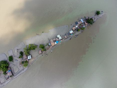 Aerial view of the narrow Kalabagi strip featuring small huts and wooden boats along the murky riverbanks in Khulna District Khulna Division Bangladesh.