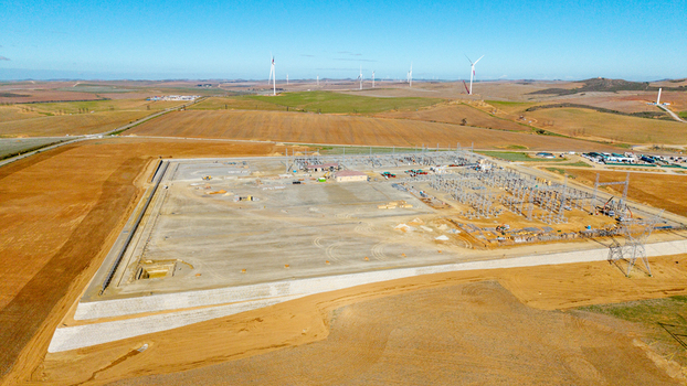 Aerial view of an electrical substation and wind farm infrastructure with turbines scattered across rolling hills under a clear blue sky Swellendam Western Cape South Africa. Aerial view of an electrical substation and wind farm infrastructure with turbines scattered across rolling hills under a clear blue sky Swellendam Western Cape South Africa.