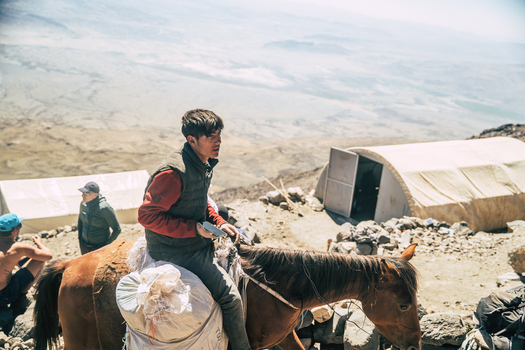 Turkey 15 August 2023 View of a young man riding a horse at a high altitude base camp on Mount Ararat in Turkey with tents and rocky mountain slopes in the background. Turkey 15 August 2023 View of a young man riding a horse at a high altitude base camp on Mount Ararat in Turkey with tents and rocky mountain slopes in the background.