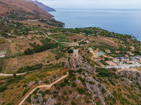 Aerial view of an ancient stone watchtower perched on a rocky hill overlooking the Mediterranean coastline with scattered houses and vegetation in Palermo Sicily Italy. Aerial view of an ancient stone watchtower perched on a rocky hill overlooking the Mediterranean coastline with scattered houses and vegetation in Palermo Sicily Italy.