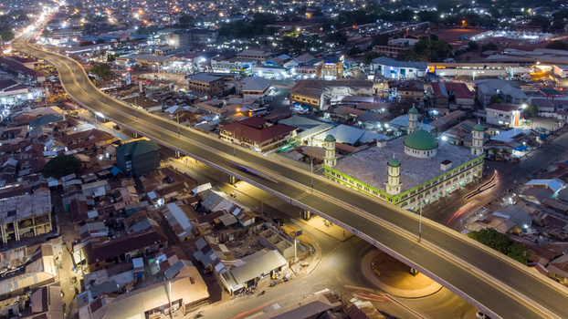 Aerial view of the illuminated Tamale Central Mosque situated next to an elevated highway with city lights and traffic streaks in the urban landscape of Tamale Northern Region Ghana. Aerial view of the illuminated Tamale Central Mosque situated next to an elevated highway with city lights and traffic streaks in the urban landscape of Tamale Northern Region Ghana.