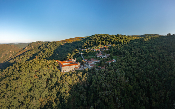 Aerial view of the Monastery of Santo Estevo de Ribas de Sil nestled in the lush green hills of the Ribeira Sacra with historic stone architecture in O Covelo Ourense Spain.