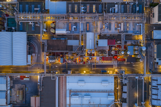 Aerial view of datacenter facility with industrial infrastructure complex piping systems and illuminated rooftops at night Settecamini Lazio Italy.