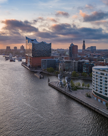 Aerial view of the Elbphilharmonie concert hall and the Strandkai district along the Elbe river under a sunset sky in Hamburg Hamburg Germany. Aerial view of the Elbphilharmonie concert hall and the Strandkai district along the Elbe river under a sunset sky in Hamburg Hamburg Germany.