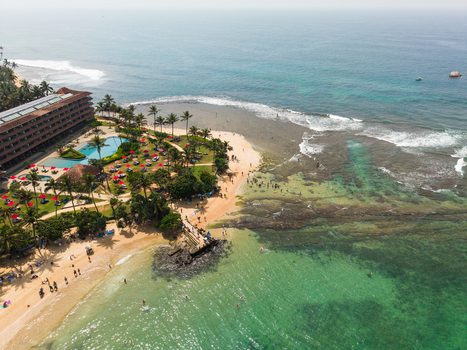 Aerial view of a tropical beach resort with palm trees swimming pools and turquoise ocean water Hikkaduwa Southern Province Sri Lanka. Aerial view of a tropical beach resort with palm trees swimming pools and turquoise ocean water Hikkaduwa Southern Province Sri Lanka.