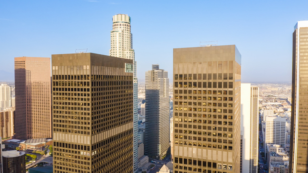 Aerial view of the Los Angeles skyline featuring the US Bank Tower and surrounding modern skyscrapers under a clear blue sky in Los Angeles California United States.