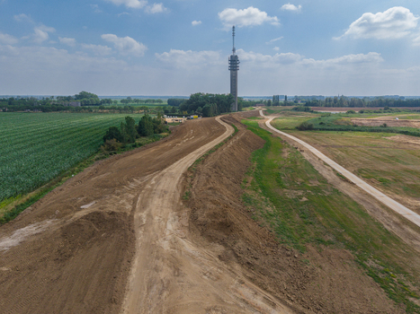 Aerial view of a tall communication tower rising above rural agricultural fields and dirt paths in the Netherlands. Aerial view of a tall communication tower rising above rural agricultural fields and dirt paths in the Netherlands.