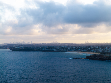 Aerial view of the coastline at Dee Why with the distant Sydney skyline visible under a cloudy sky in Dee Why New South Wales Australia. Aerial view of the coastline at Dee Why with the distant Sydney skyline visible under a cloudy sky in Dee Why New South Wales Australia.
