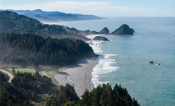 Aerial view of Arizona Beach on the rugged Southern Oregon Coast featuring evergreen forest sandy shoreline rocky sea stacks and misty coastal hills near Port Orford Oregon United States. Aerial view of Arizona Beach on the rugged Southern Oregon Coast featuring evergreen forest sandy shoreline rocky sea stacks and misty coastal hills near Port Orford Oregon United States.