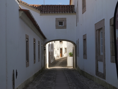 View of a narrow cobblestone street passing under a stone archway between traditional white washed buildings in the historic village of Marvao Portalegre District Portugal. View of a narrow cobblestone street passing under a stone archway between traditional white washed buildings in the historic village of Marvao Portalegre District Portugal.