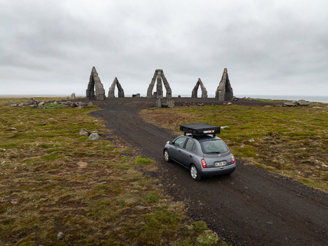 Aerial view of Arctic Henge monument with a car and roof tent on a gravel road in the mossy landscape of Raufarhofn Nordurthing Iceland.