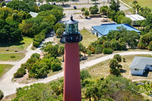 Aerial view of Jupiter Inlet Lighthouse with people on the gallery surrounded by lush green trees and coastal paths Jupiter Florida United States. Aerial view of Jupiter Inlet Lighthouse with people on the gallery surrounded by lush green trees and coastal paths Jupiter Florida United States.