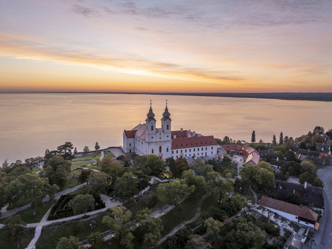 Aerial view of Tihany Abbey overlooking Lake Balaton at sunset with lush trees and historic architecture in Tihany Hungary. Aerial view of Tihany Abbey overlooking Lake Balaton at sunset with lush trees and historic architecture in Tihany Hungary.