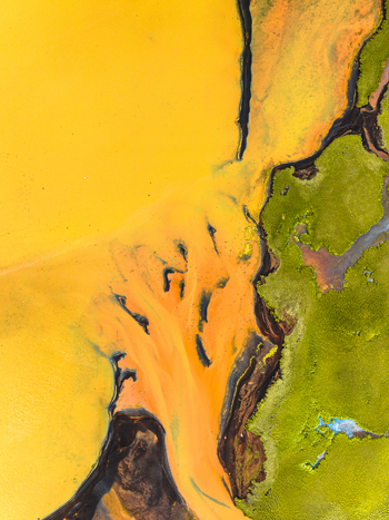 Aerial view of a vibrant glacial river with sediment rich yellow and orange water flowing through dark volcanic sand and bright green mossy terrain in Iceland. Aerial view of a vibrant glacial river with sediment rich yellow and orange water flowing through dark volcanic sand and bright green mossy terrain in Iceland.