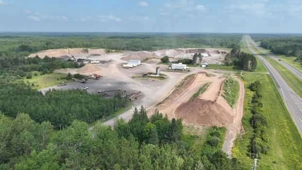 Aerial view of a quarry site contrasting starkly against the surrounding lush greenery and a distant highway Grand Rapids Minnesota United States.