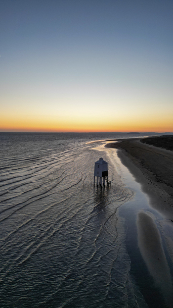 Aerial view of the Burnham on Sea Low Lighthouse standing on the sandy beach at sunset with calm waves reflecting the golden light in Burnham on Sea England United Kingdom. Aerial view of the Burnham on Sea Low Lighthouse standing on the sandy beach at sunset with calm waves reflecting the golden light in Burnham on Sea England United Kingdom.