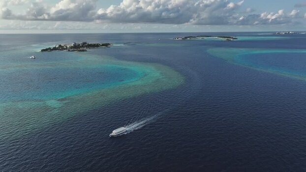 Aerial view of a boat cruising near tropical islands Maldives. Aerial view of a boat cruising near tropical islands Maldives.