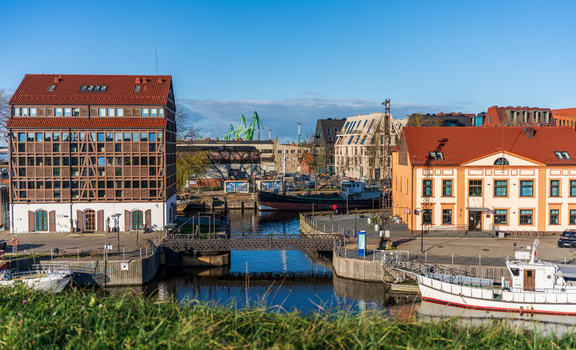 View of the Dane River canal with historic buildings a small pedestrian bridge and moored boats under a clear blue sky in Klaipeda Klaipeda County Lithuania. View of the Dane River canal with historic buildings a small pedestrian bridge and moored boats under a clear blue sky in Klaipeda Klaipeda County Lithuania.