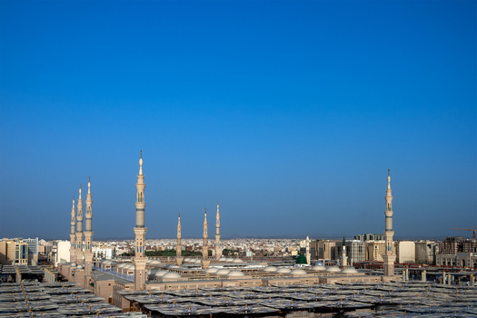 View of Al Masjid e Nabawi with its iconic minarets and expansive courtyard under a clear blue sky in Madinah Al Madinah Province Saudi Arabia.