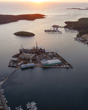Aerial view of the industrial Pola Port shipyard with cranes and docks surrounded by calm Adriatic Sea waters at sunset in Pula Istarska zupanija Croatia. Aerial view of the industrial Pola Port shipyard with cranes and docks surrounded by calm Adriatic Sea waters at sunset in Pula Istarska zupanija Croatia.