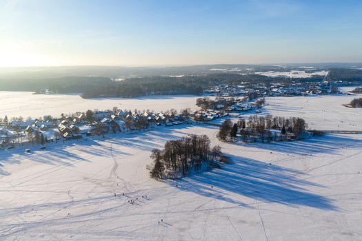Aerial view of the snow covered town and frozen Lake Galve with people walking on the ice under a clear blue sky Trakai Vilniaus apskritis Lithuania.