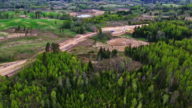 Aerial view of wind turbine foundation construction site in a rural landscape with surrounding forests and green fields in Latvia. Aerial view of wind turbine foundation construction site in a rural landscape with surrounding forests and green fields in Latvia.