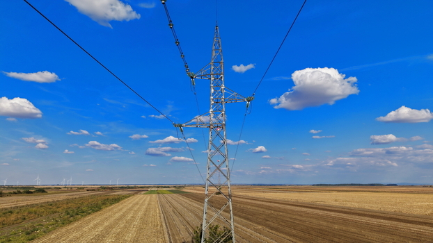 Aerial view of a high voltage electricity pylon with signal balls for marking transmission lines set against a rural landscape with distant wind turbines in Bavaniste Vojvodina Serbia. Aerial view of a high voltage electricity pylon with signal balls for marking transmission lines set against a rural landscape with distant wind turbines in Bavaniste Vojvodina Serbia.