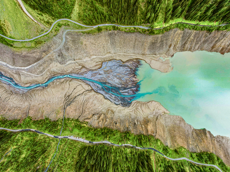 Aerial view of the river delta with turquoise glacial water flowing into a reservoir surrounded by dense pine forests and winding mountain roads in Prutz Tyrol Austria. Aerial view of the river delta with turquoise glacial water flowing into a reservoir surrounded by dense pine forests and winding mountain roads in Prutz Tyrol Austria.