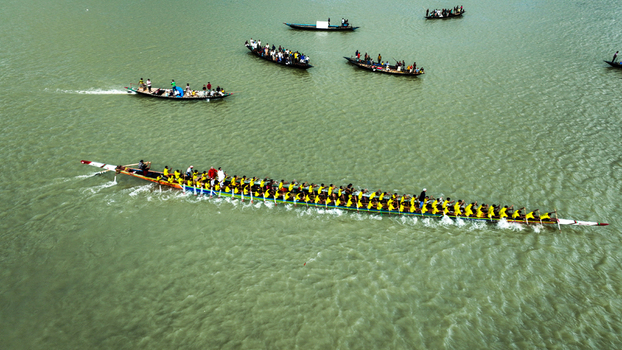 Baghabari Rajshahi Division Bangladesh 20 August 2022 Aerial view of a traditional long boat race with rowers in yellow shirts paddling in unison on the river.