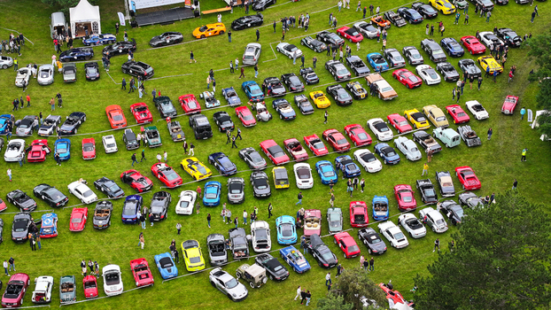 La Chapelle de Guinchay France 01 June 2024 Aerial view of a large gathering of colorful sports and classic cars parked in rows on a green field during an outdoor car show.