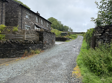 View of traditional stone cottages and a gravel path lined with dry stone walls under an overcast sky in Hawes England United Kingdom. View of traditional stone cottages and a gravel path lined with dry stone walls under an overcast sky in Hawes England United Kingdom.