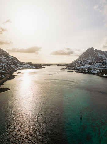 Aerial view of the bridge over the serene deep waters against the backdrop of snow dusted mountains Kåkernbrua Nordland Norway. Aerial view of the bridge over the serene deep waters against the backdrop of snow dusted mountains Kåkernbrua Nordland Norway.